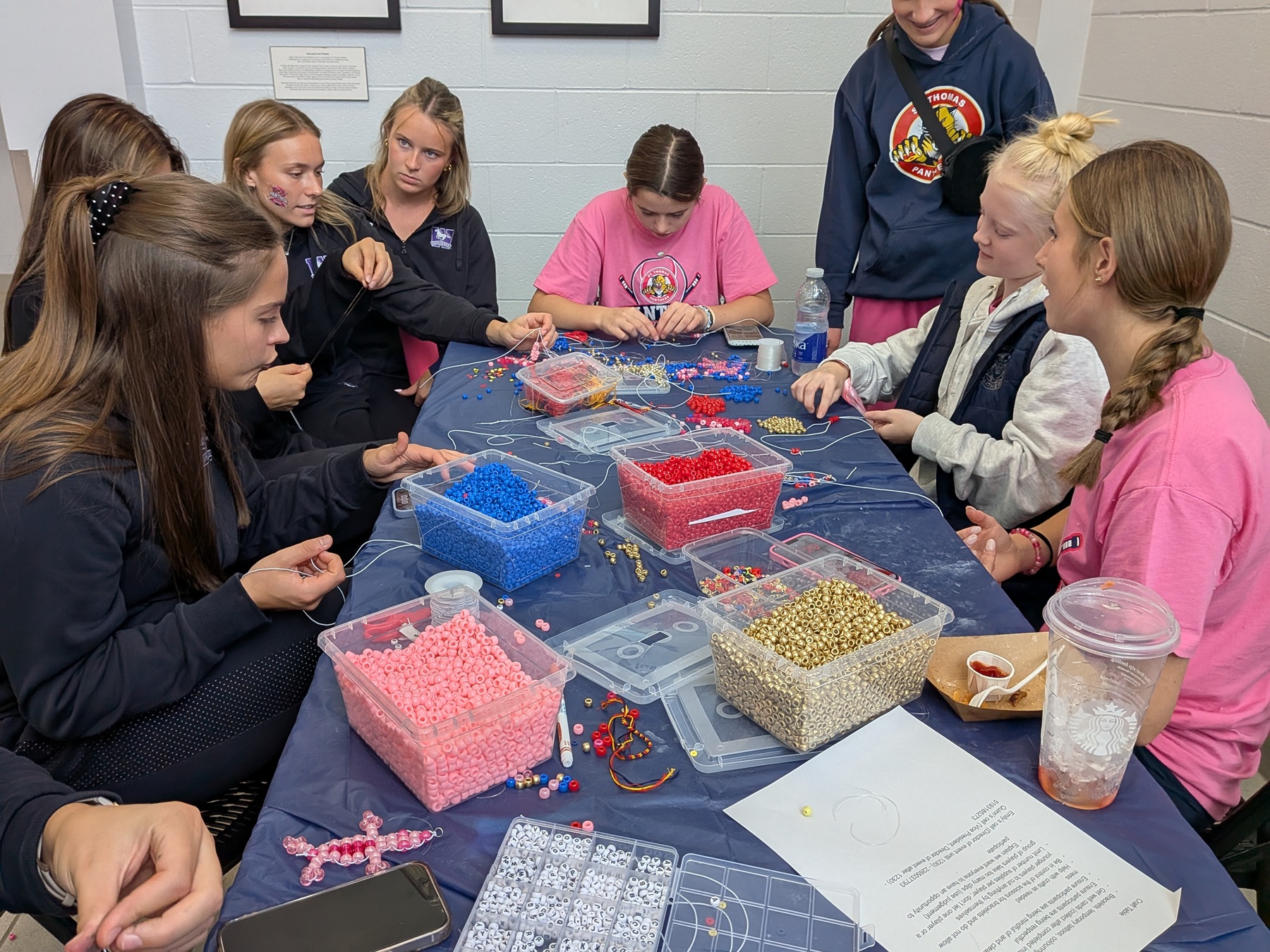 Members of the Western Mustangs women's hockey team help St. Thomas Panthers create bracelets.