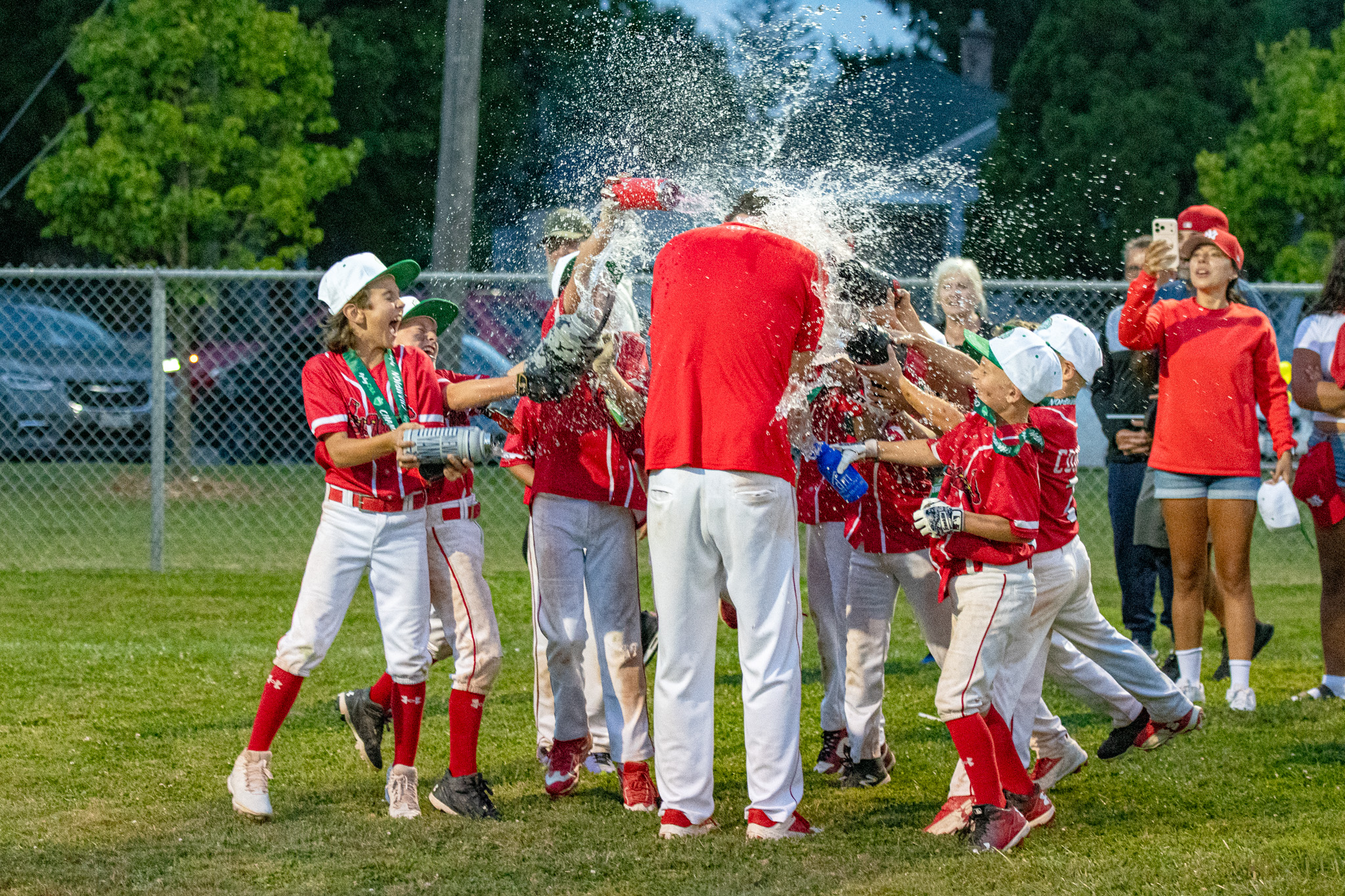 The Cardinals players celebrate by drenching head coach Mike Wakefield from 12 water bottles from all angles.